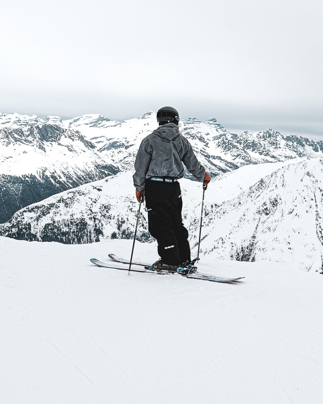 The skier behind OffPisteEast standing on a ridge, looking out over the mountains